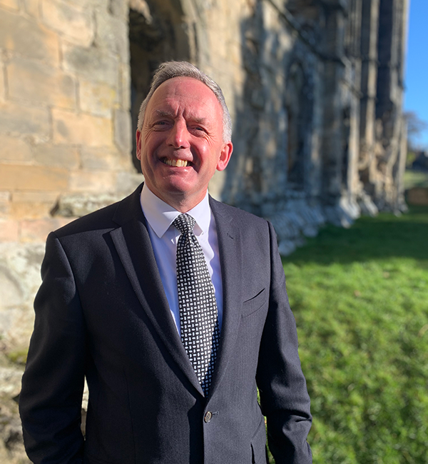 James Blenkiron - smartly dressed man with gray hair smiling